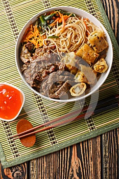 Bowl of traditional Vietnamese noodle salad Bun Bo Nam Bo, with beef, rice noodles, fresh herbs, pickled vegetables and fish sauce