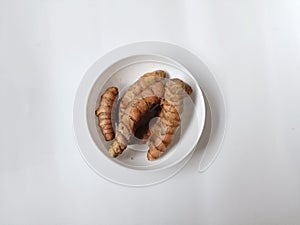 A bowl of tumeric on white bowl with a white background