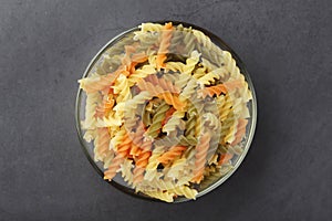 A bowl with uncooked pasta fusilli tricolore