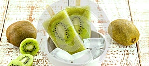 Bowl of vanilla and kiwi yogurt popsicles on a white rustic wooden background  unsweetened ice cream  natural homemade