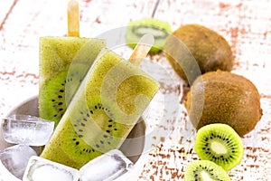 Bowl of vanilla and kiwi yogurt popsicles on a white rustic wooden background  unsweetened ice cream  natural homemade