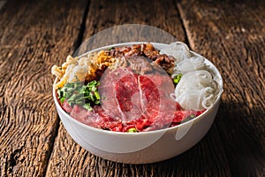 Bowl of vietnamese pho rice noodle with sliced fresh beef and stewed beef