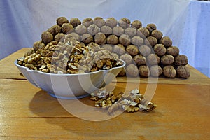 A bowl with walnut kernels and a lot of walnuts folded in the form of a prism