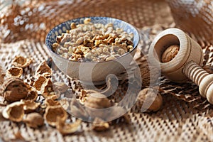 A bowl of walnuts placed on a table with shells and a wooden nutcracker lying around in a rustic style