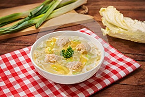 Bowl of wanton soup with fried fish balls on the table in restaurant