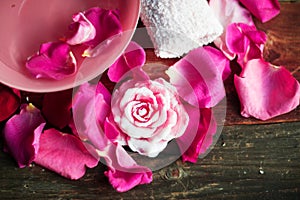 Bowl with water and rose petals on wooden table