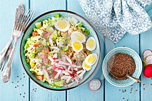 Bowl with wheat porridge, boiled quail eggs and fresh vegetable salad of radish, corn, sweet pepper and chinese cabbage. Healthy a