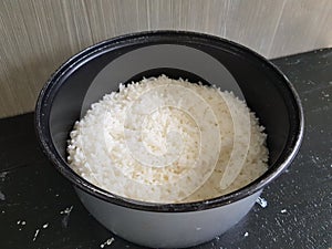 A bowl of white rice is on the black tabl