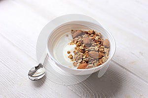 Bowl of whole grain granola with yogurt on white background, top view