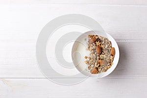 Bowl of whole grain granola with yogurt on white background, top view