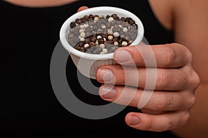 Bowl of Whole Peppercorns in a Female Hand. Gently holding a ramekin filled with assorted whole peppercorns