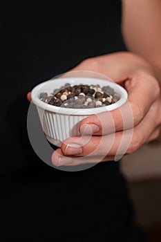 Bowl of Whole Peppercorns in a Female Hand. Gently holding a ramekin filled with assorted whole peppercorns