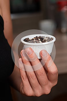 Bowl of Whole Peppercorns in a Female Hand. Gently holding a ramekin filled with assorted whole peppercorns