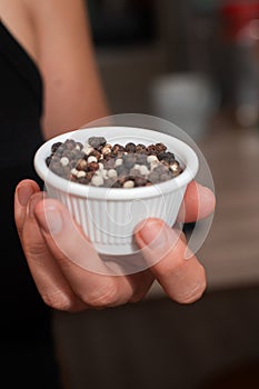 Bowl of Whole Peppercorns in a Female Hand. Gently holding a ramekin filled with assorted whole peppercorns