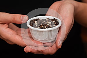 Bowl of Whole Peppercorns in a Female Hands. Gently holding a ramekin filled with assorted whole peppercorns