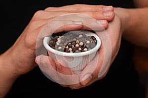 Bowl of Whole Peppercorns in a Female Hands. Gently holding a ramekin filled with assorted whole peppercorns