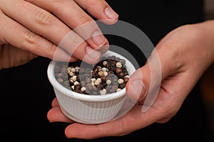 Bowl of Whole Peppercorns in a Female Hands. Gently holding a ramekin filled with assorted whole peppercorns