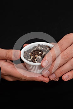 Bowl of Whole Peppercorns in a Female Hands. Gently holding a ramekin filled with assorted whole peppercorns