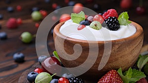 Bowl of yogurt with wild berries on dark wooden background