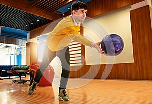 Bowler player prepares to release purple ball in modern bowling alley