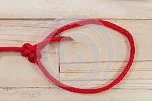 Bowline knot made from red synthetic rope, tightening on wooden