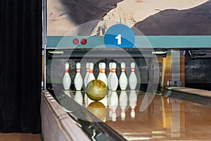 Bowling ball rolls along a wooden path to the pins. Golden ball knocks down