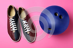 Bowling ball and shoes on pink background