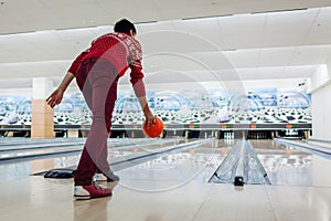 Bowling game. Man having fun playing bowling in club throwing ball on lane. Kegling