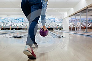 Bowling game. Woman having fun playing bowling in club throwing ball. Close up of legs and shoes