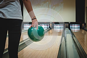 Bowling girl prepares for her throw on a specially modified bowling alley. Spending free time. A woman holds a green ball and