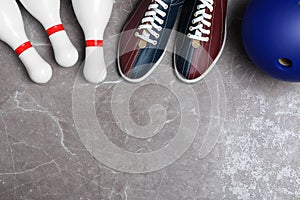 Bowling shoes, pins and ball on grey marble table, flat lay. Space for text