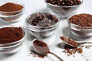 Bowls of beans, instant and ground coffee on white marble table, closeup