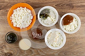 Bowls with cottage cheese, jam, condensed milk, boiled condensed milk on table. Top view