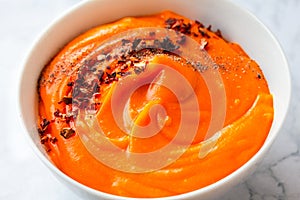 Bowls of creamy delicious pumpkin soup with chili flakes pepper. Autumn comfort food concept