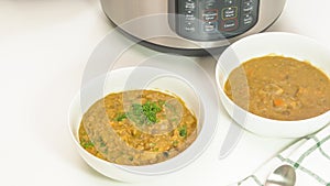 Bowls of a creamy lentil soup close up on white kitchen table. Multi cooker lentil soup recipe