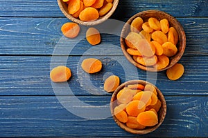Bowls with dried apricots on wooden table photo