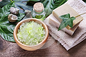 Bowls of green sea salt, bottle of essential oil and bars of soap
