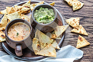 Bowls of guacamole and queso with tortilla chips photo