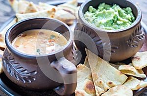 Bowls of guacamole and queso with tortilla chips photo