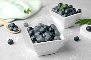 Bowls of tasty blueberries and spoon on marble table