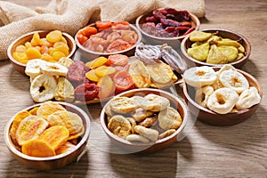 bowls of various dried fruits on wooden background