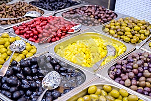 Bowls of various olives for sale at a market place. Organic, healthy, vegetarian diet food concept background. Selective focus