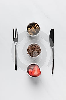 Bowls with walnuts, grated chocolate and strawberries between fork and knife