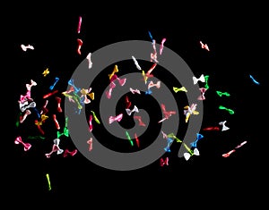 Bows flying in air. Many small ribbon in red, blue, pink, yellow throw explosion. Small Bow floating abstract black background