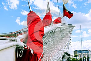 Bowsprit and gathered red sail of the sailing ship.