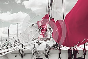 Bowsprit and gathered red sail of the sailing ship.