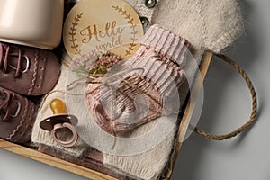 Box with baby clothes, shoes and accessories on light background, top view
