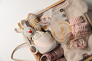 Box with baby clothes, shoes and accessories on light background, top view