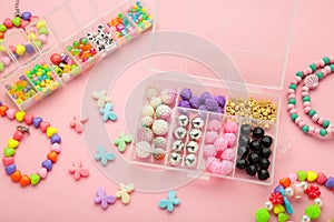 Box with beads to create hand made jewelry for child on pink background. Making bracelet. Handmade accessories