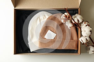 Box with beanies and cotton on white background